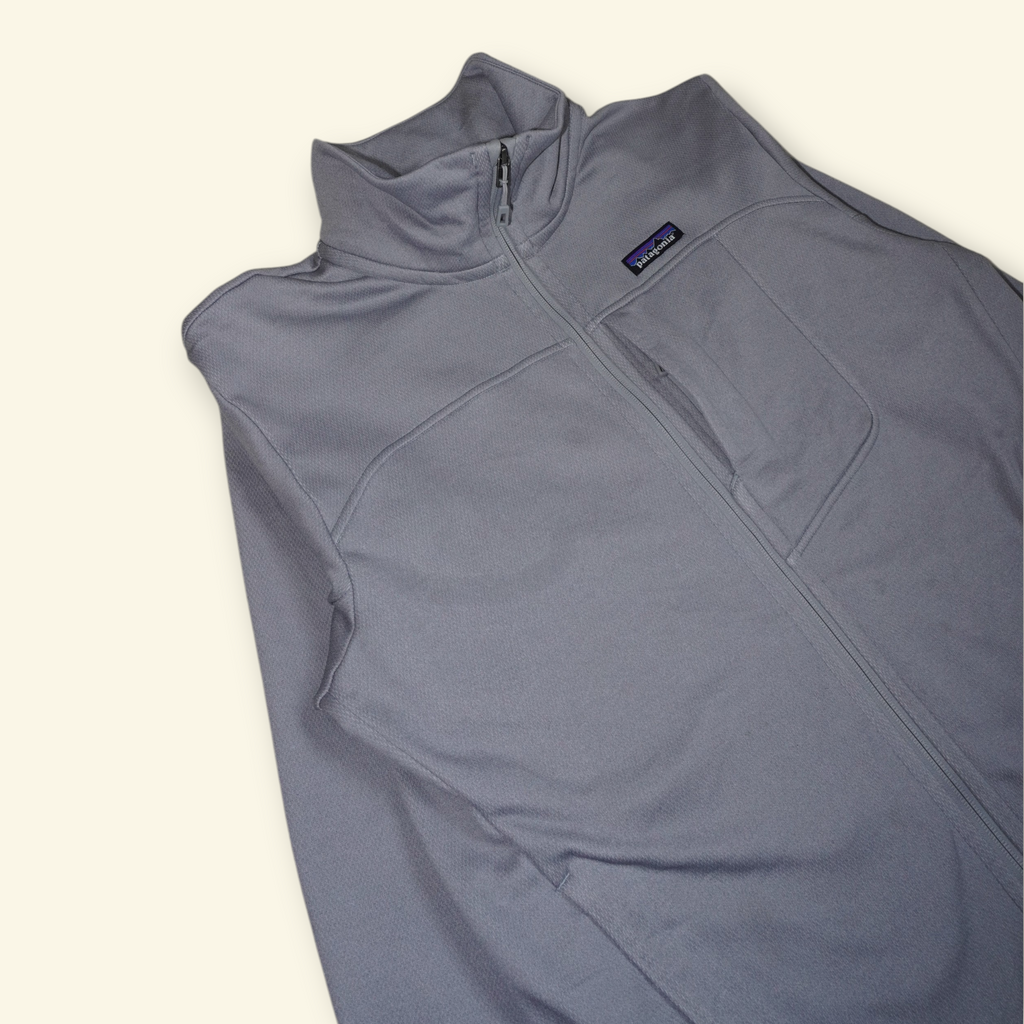 Chaqueta Patagonia Ukiah gris de poliéster reciclado con cuello alto y cierre frontal, estilo urbano y técnico.