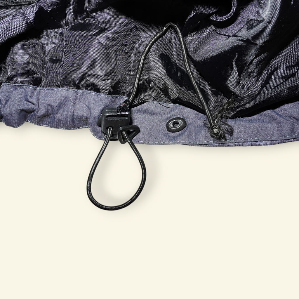 Detalle del ajustador de cordón en la chamarra vintage Mi tienda The North Face Summit Series Gore-Tex gris y negro
