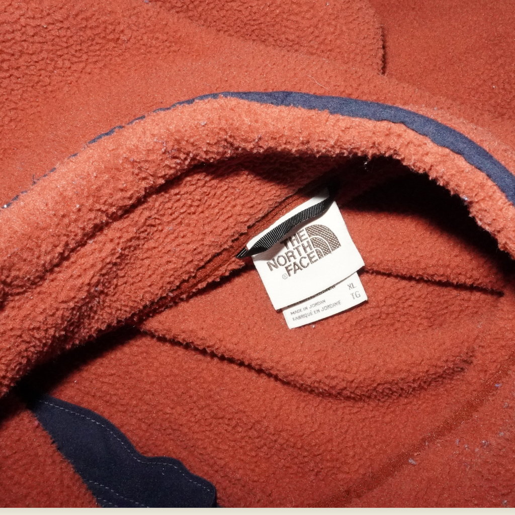 Etiqueta interior y forro polar naranja de The North Face en Mi tienda, mostrando la marca y talla XL