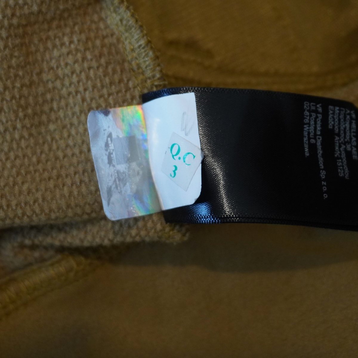 Etiqueta interior de autenticidad en chamarra color caqui de Mi tienda The North Face con holograma de seguridad